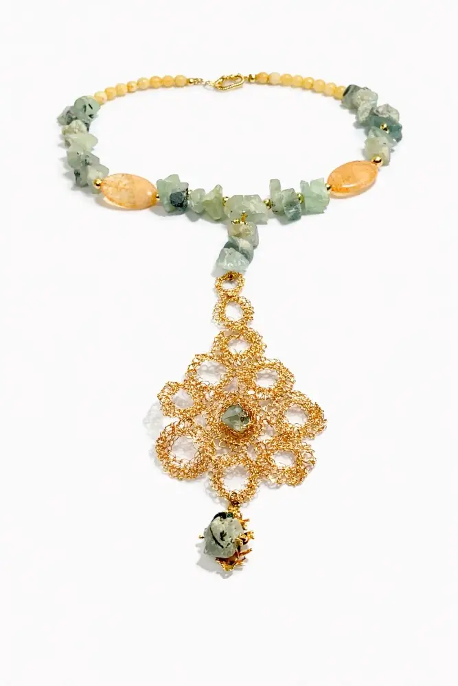 Collar artesanal de piedras naturales en tonos verde menta y crema, realzado con un gran colgante floral de filigrana dorada.